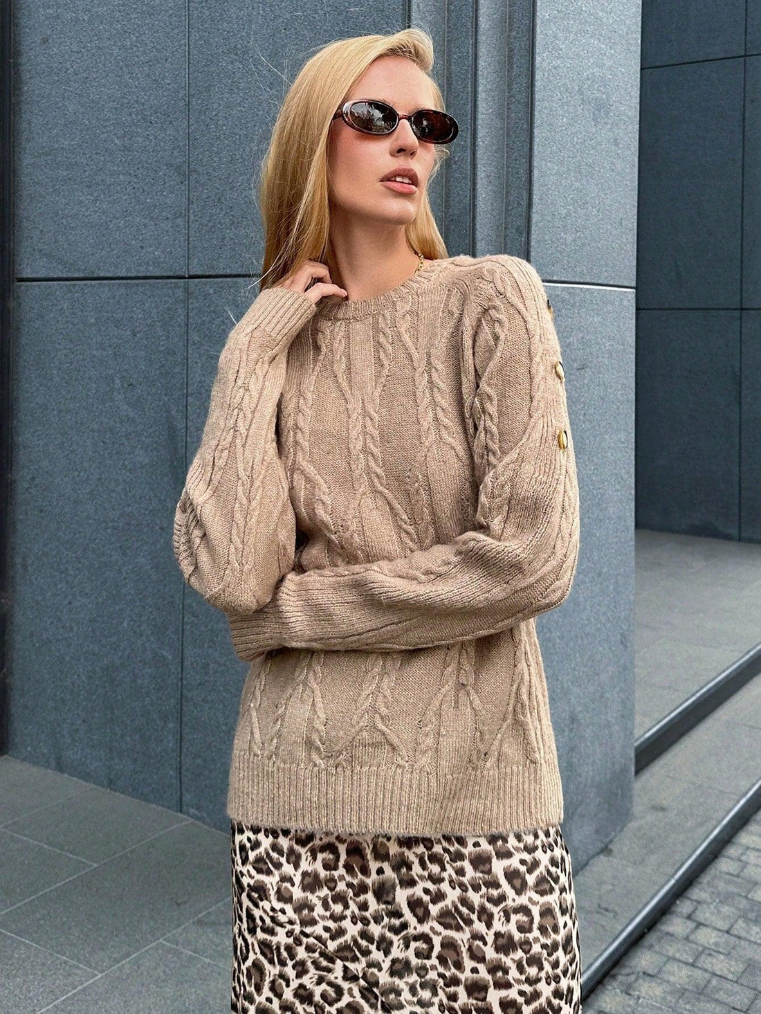 woman wearing a tan knit sweater with a textured pattern and blue jeans