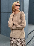 woman wearing a tan knit sweater with a textured pattern and blue jeans