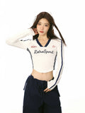 Close-up of a model wearing a white long-sleeve crop top with graphic detail.