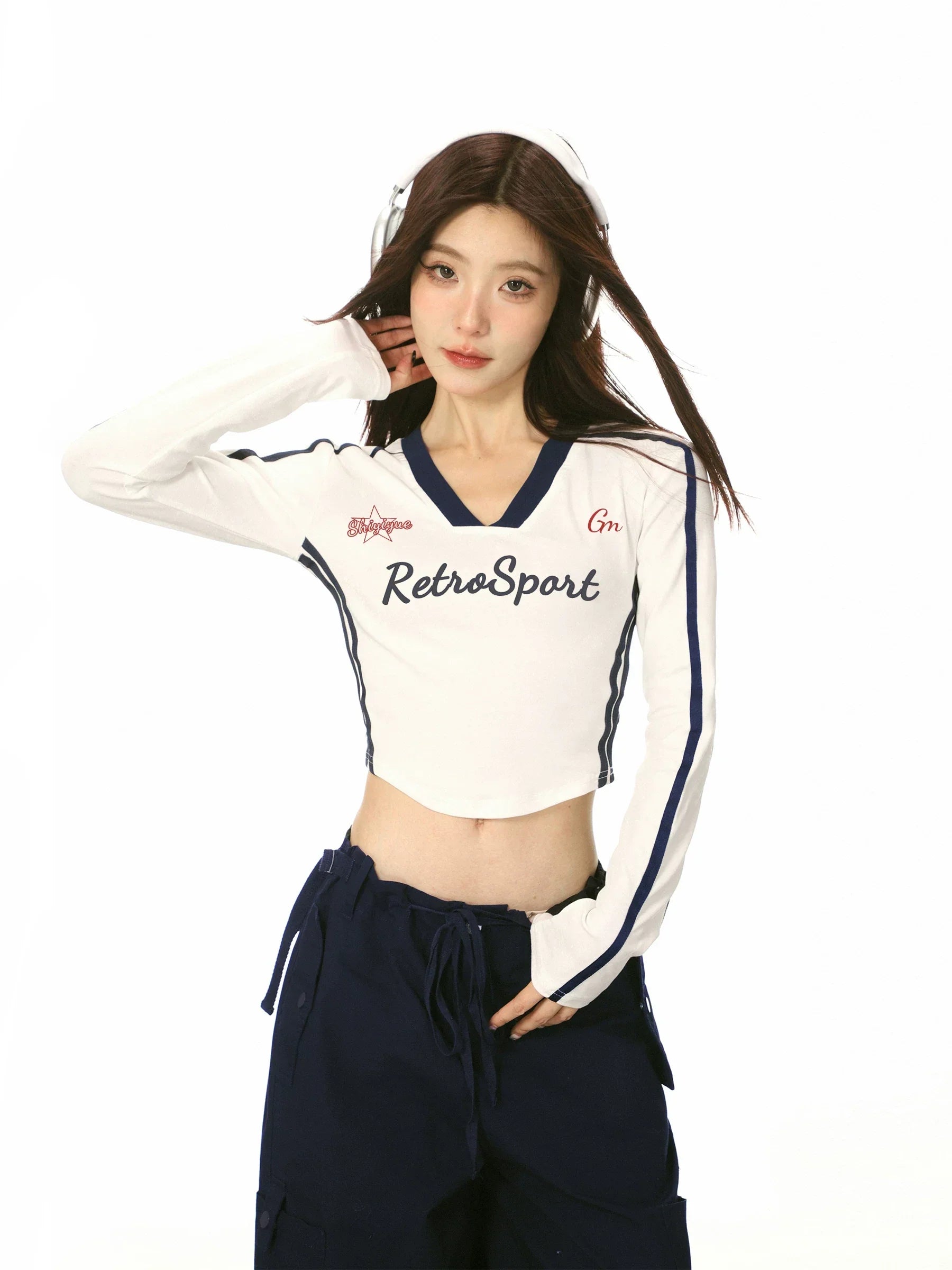 Close-up of a model wearing a white long-sleeve crop top with graphic detail.