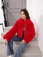 Side profile of a woman seated on stairs, showcasing the textured red faux fur jacket.