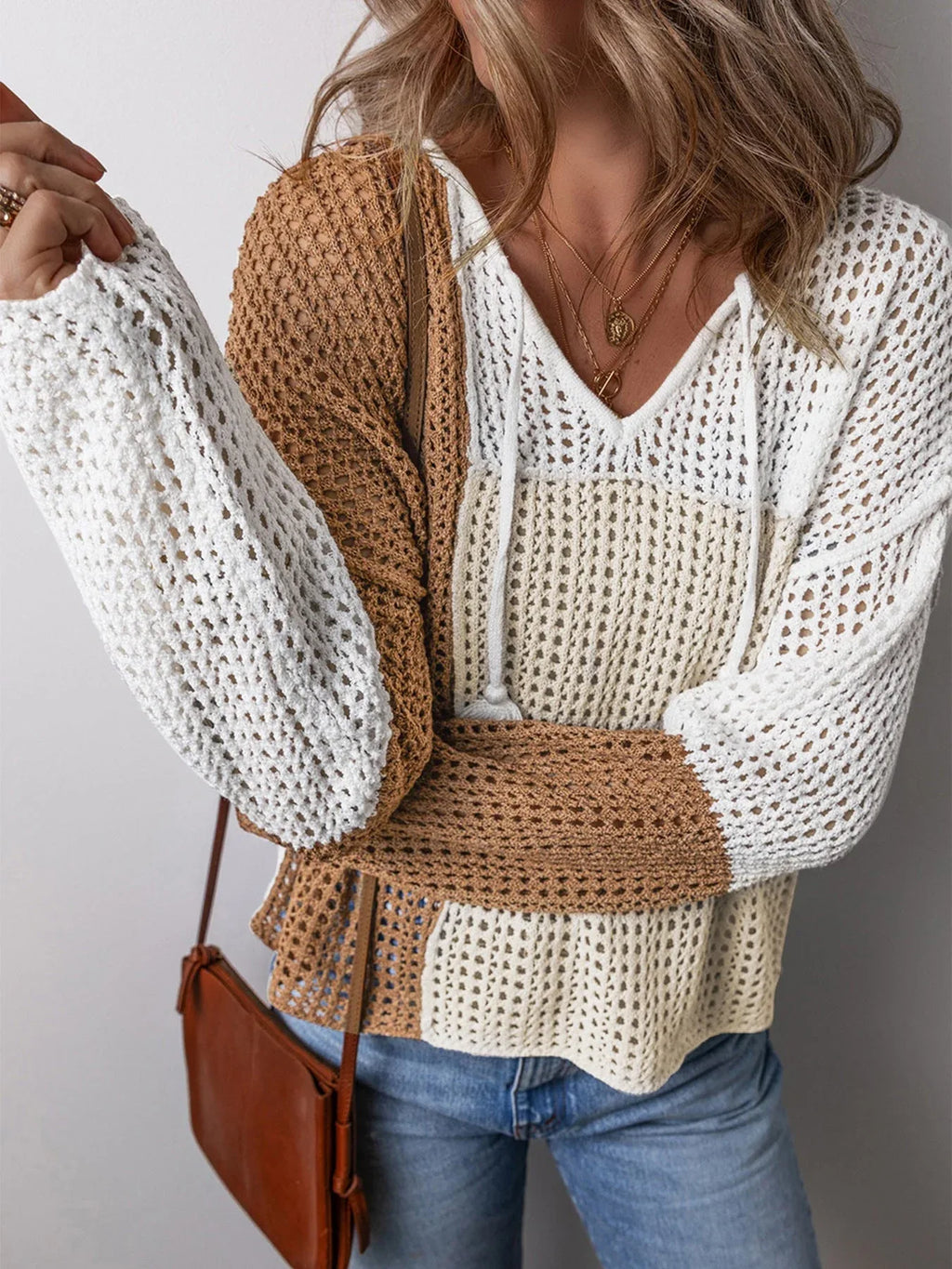 Close-up of a woman's chest and arms wearing a color block knit hoodie