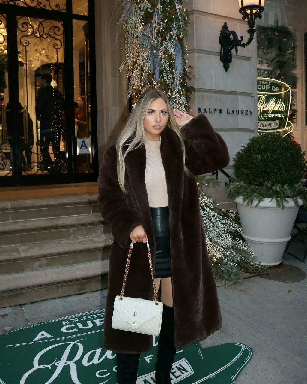 Woman wearing a long brown faux fur coat and a cream turtleneck