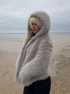 Woman with her face partially obscured by a grey hooded faux fur jacket