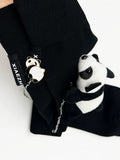 Detail shot of the 'XIAEZHI' tag and panda charm on black knee-high socks.