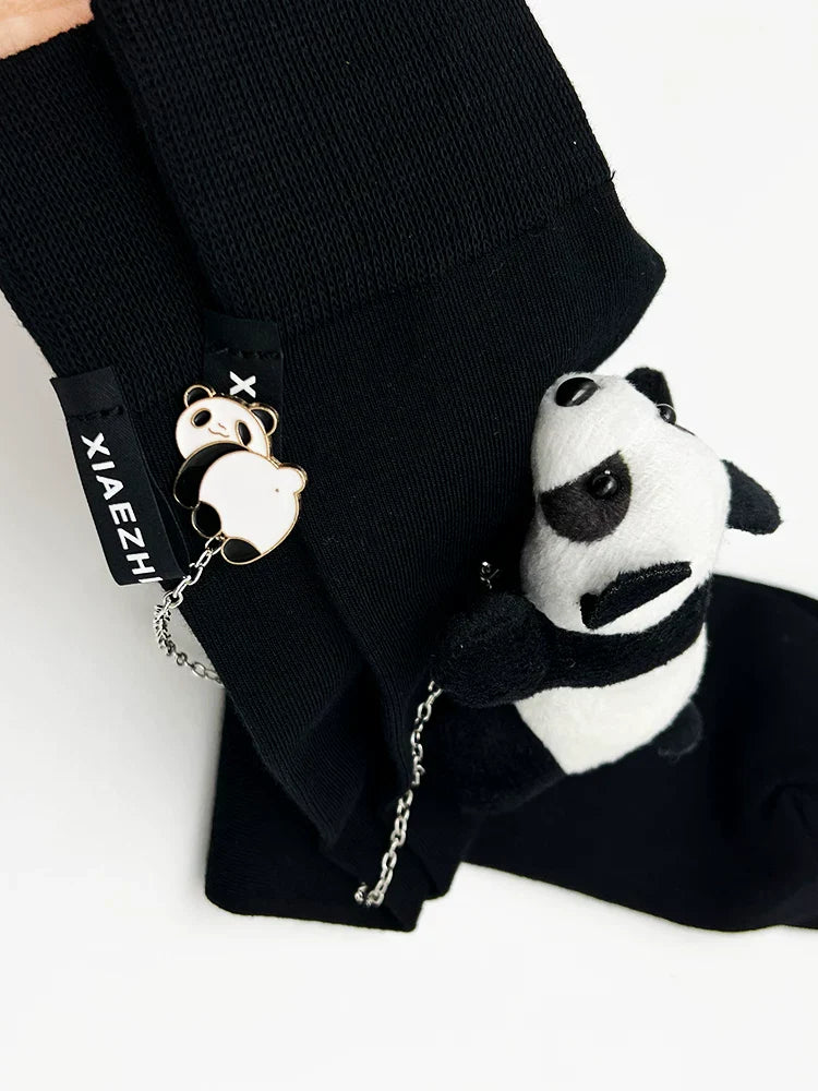Detail shot of the 'XIAEZHI' tag and panda charm on black knee-high socks.