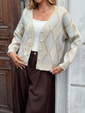 Woman showing off a cream argyle knit cardigan with a white tank top and brown pants.