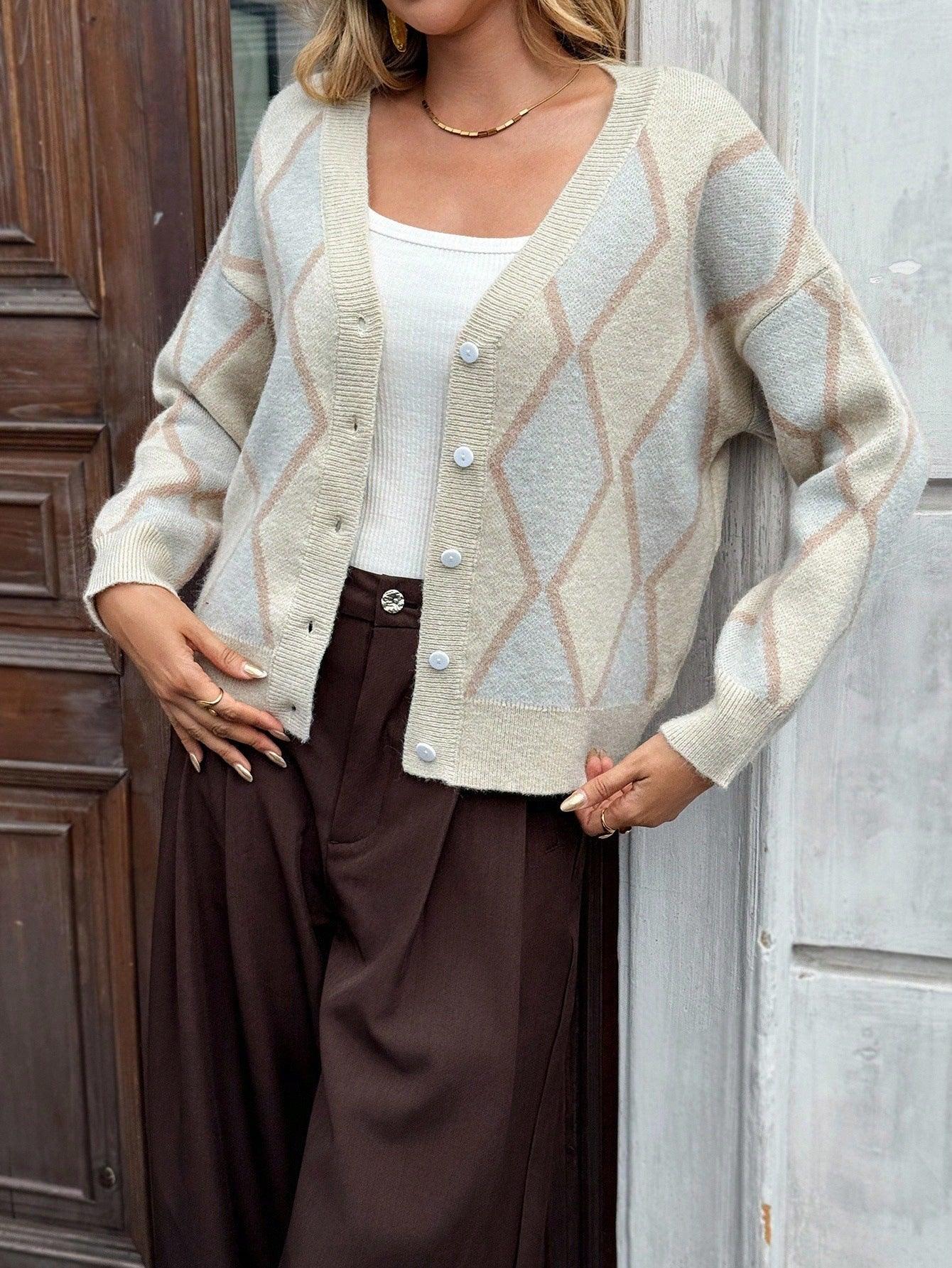 Woman showing off a cream argyle knit cardigan with a white tank top and brown pants.