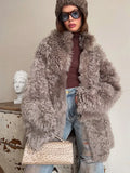 Close-up of a woman's upper body wearing a grey curly faux fur coat, highlighting the collar and texture.