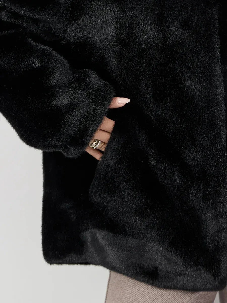 Close-up of a hand reaching into the pocket of a black faux fur jacket.
