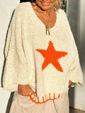 Close-up of a woman smiling, wearing an off-white knit sweater with an orange star graphic and orange trim.