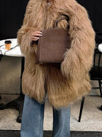 Woman in a tan shaggy faux fur coat holding a brown tote bag