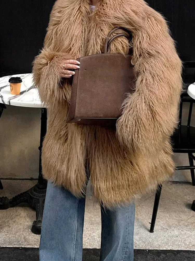 Woman in a tan shaggy faux fur coat holding a brown tote bag