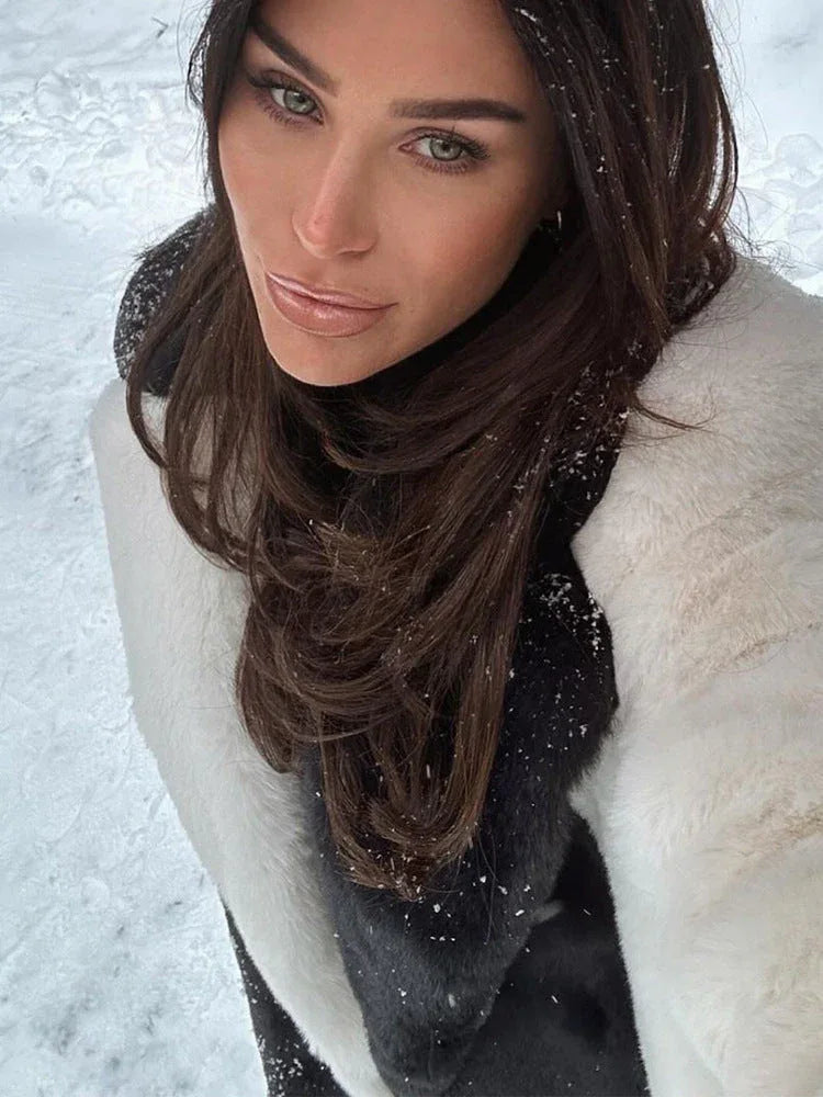 Close-up of a woman's face, wearing a black turtleneck and a white faux fur collar.
