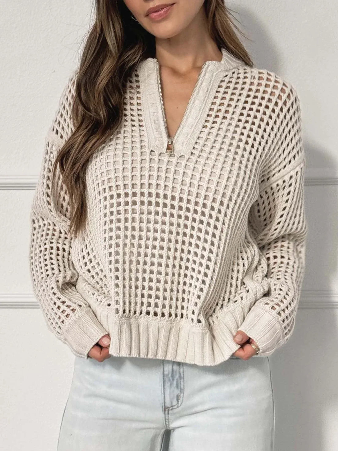 Woman wearing a cream-colored open knit quarter-zip sweater