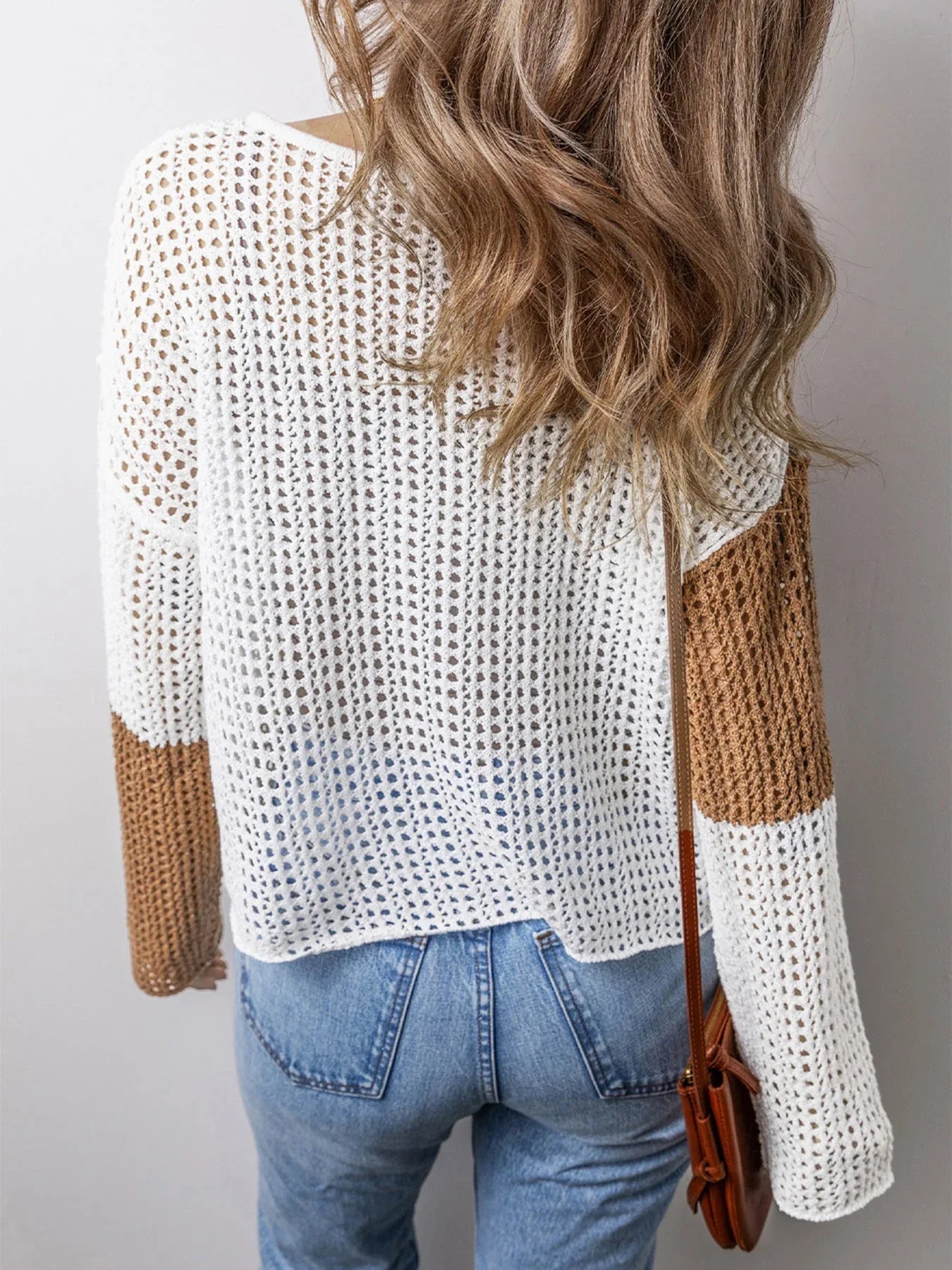 Back view of a woman in a white and brown color block knit hoodie