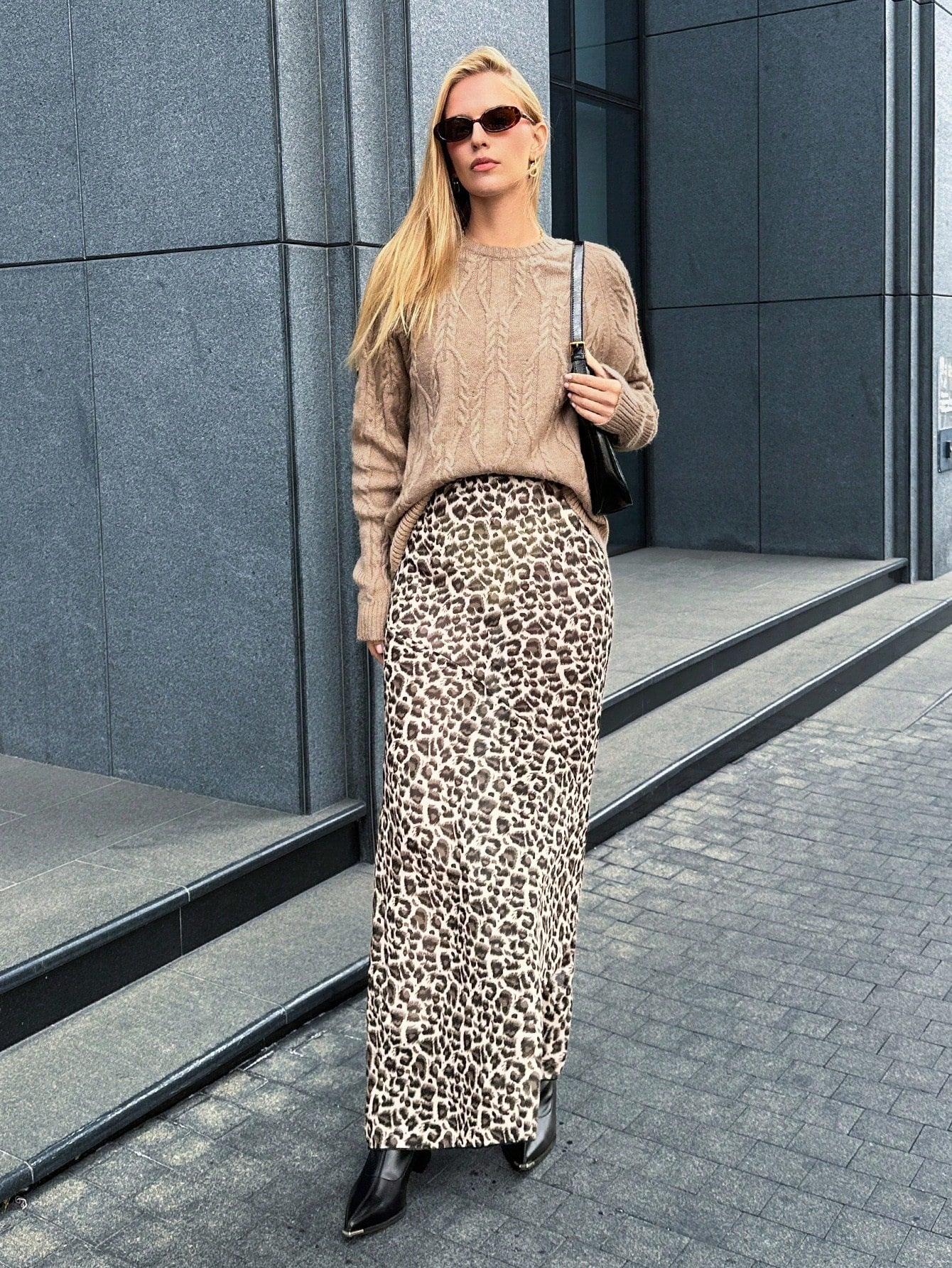 Woman holding a white clutch purse, wearing a tan textured knit sweater and blue jeans.