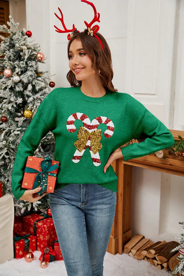Woman wearing a green knit sweater with a candy cane sequin design and a red headband with antlers.