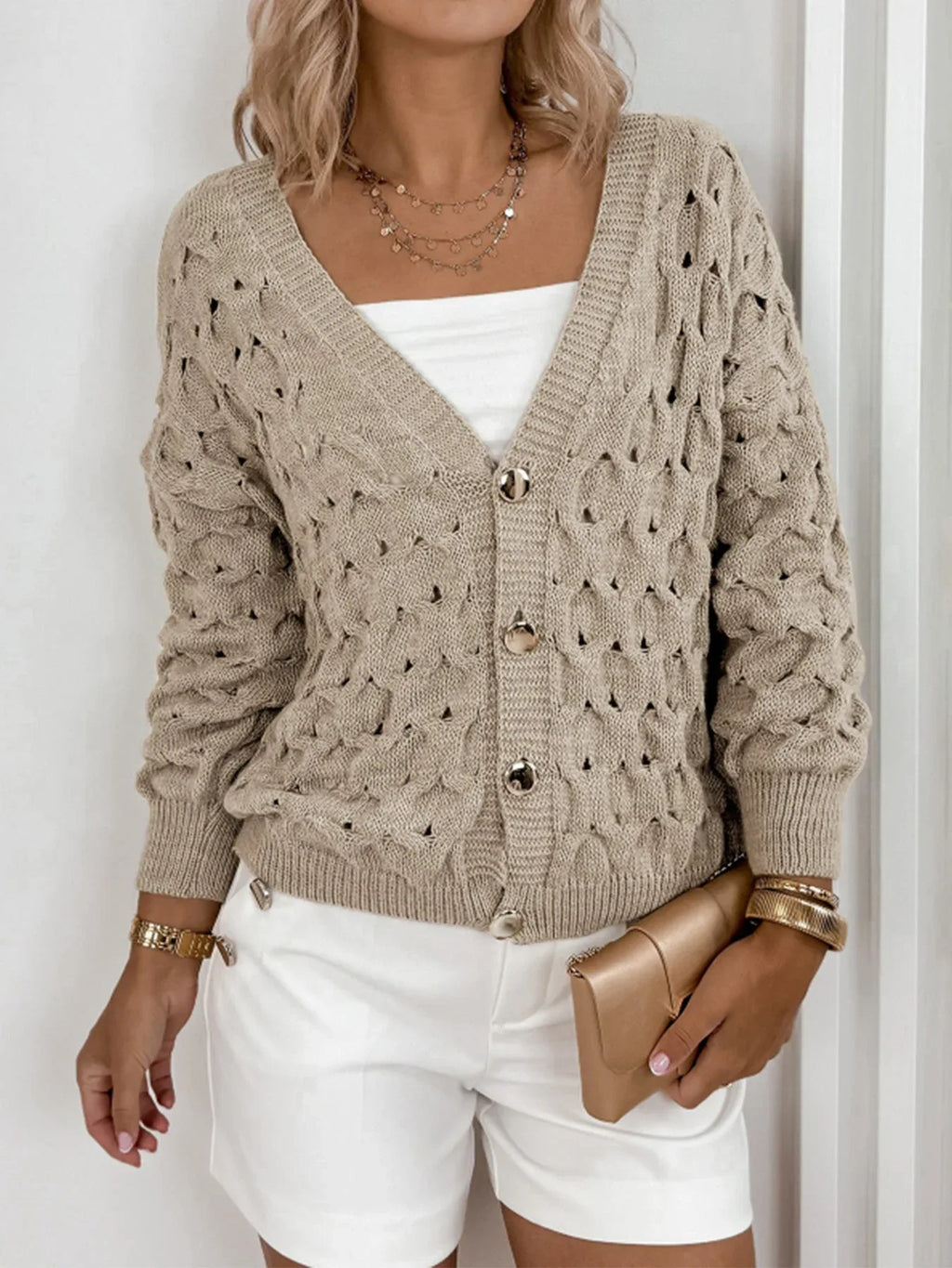 Front view of a woman in a beige open-knit cardigan, showcasing the texture and buttons.