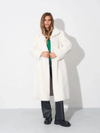 Woman wearing a white faux fur long coat with black pants.