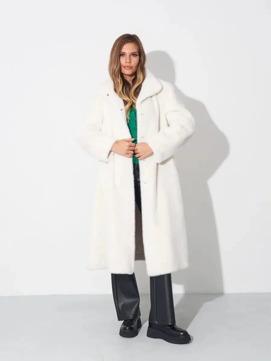 Woman wearing a white faux fur long coat with black pants.