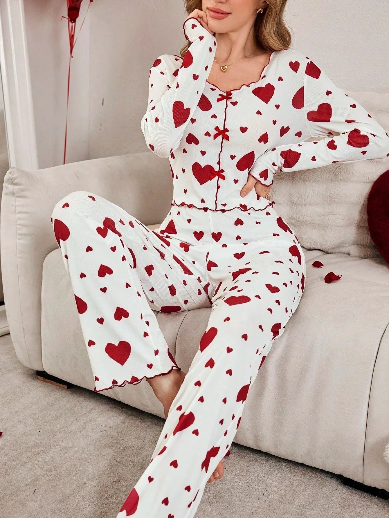 Woman sitting on a couch in heart-print pajamas, resting her chin on her hand.