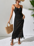Model with a straw hat holding a woven bag and wearing a black crochet maxi dress