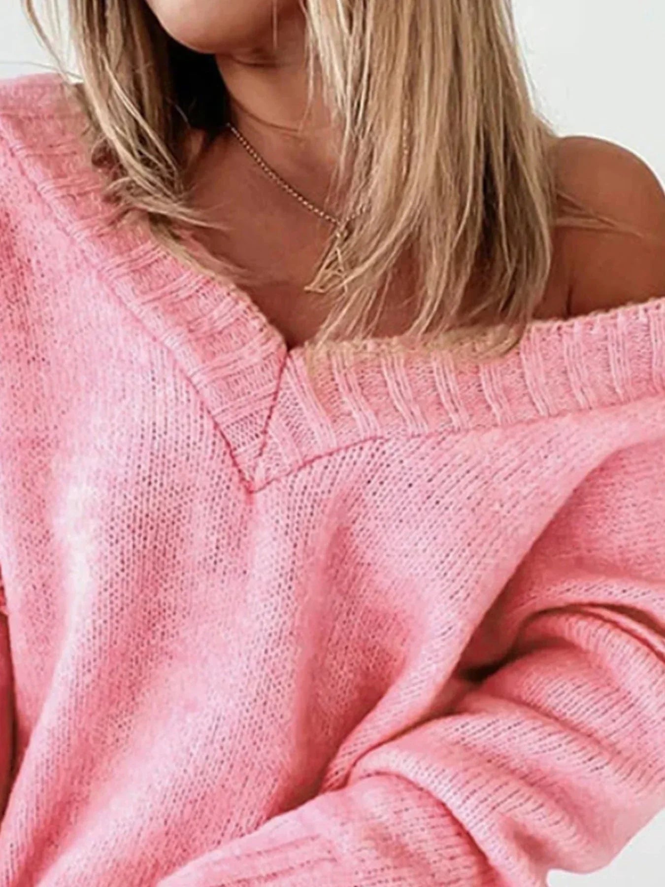 Close-up of the v-neckline and knit texture of a pink sweater.