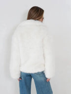 Rear view of a woman wearing a white faux fur jacket and blue jeans.