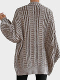 Close-up of a woman wearing a cream oversized chunky knit cardigan, showing the ribbed texture and pockets.