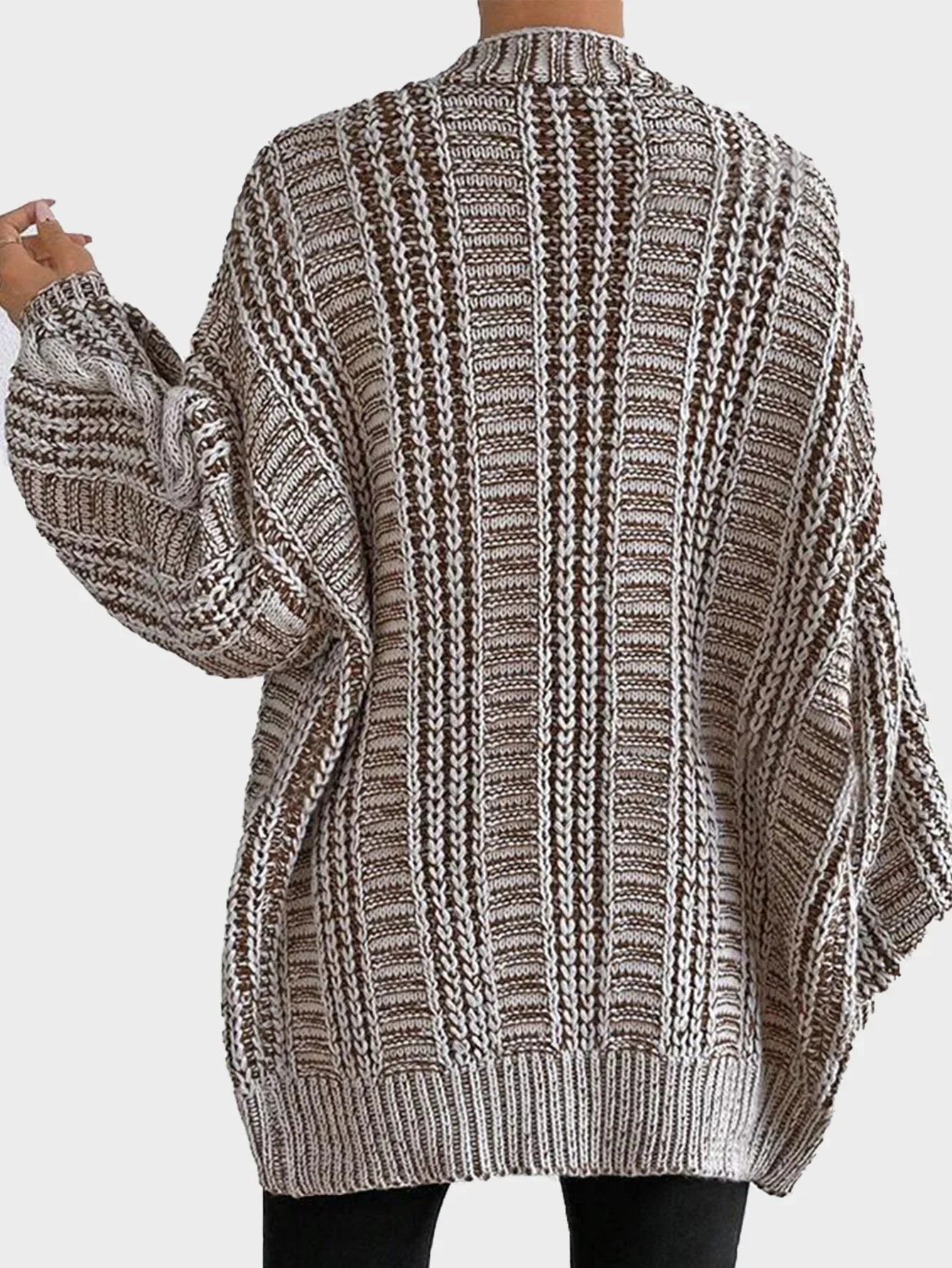 Close-up of a woman wearing a cream oversized chunky knit cardigan, showing the ribbed texture and pockets.