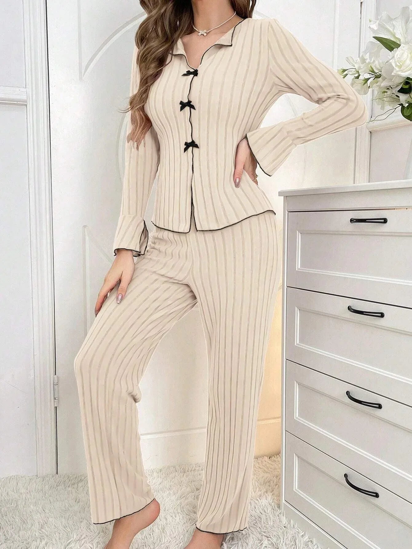 Woman wearing a white pajama set with a cherry print and lace trim. Main image