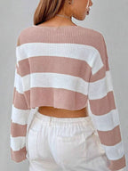 Back view of a woman in a pink and white striped cropped knit sweater with a v-neckline and long sleeves.