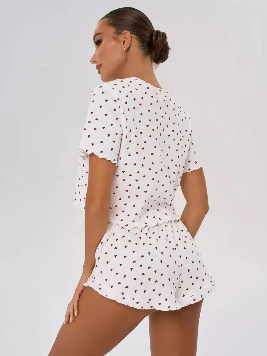 Rear view of a woman wearing a white pajama set with a red heart print and ruffled details.