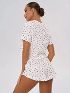 Rear view of a woman wearing a white pajama set with a red heart print and ruffled details.