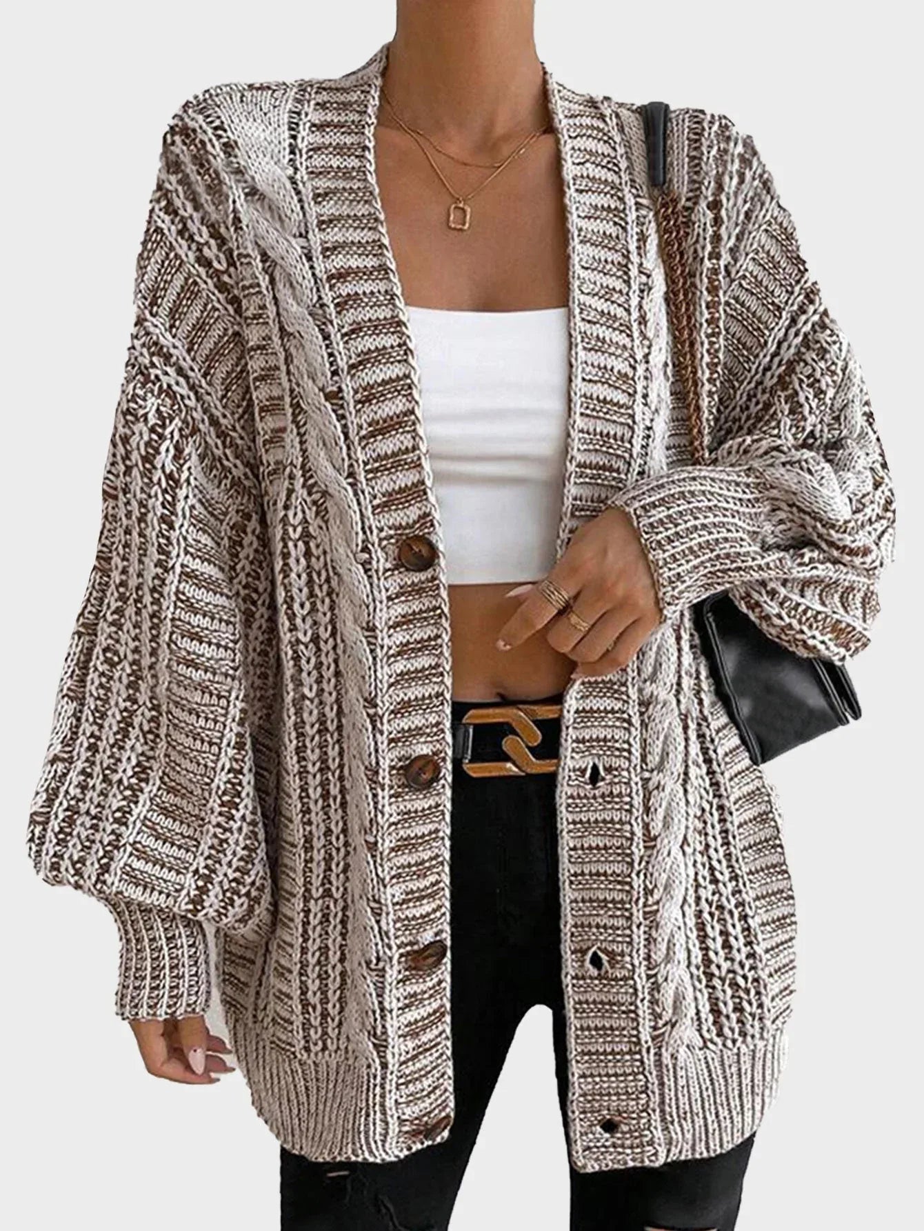 Woman posing in a cream oversized chunky knit cardigan, highlighting the open front and balloon sleeves.