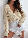 Woman wearing a beige cropped knit cardigan with V-neck and button closure.