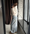Side view of a woman showcasing the cropped silhouette of a cream faux fur jacket.