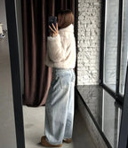 Side view of a woman showcasing the cropped silhouette of a cream faux fur jacket.