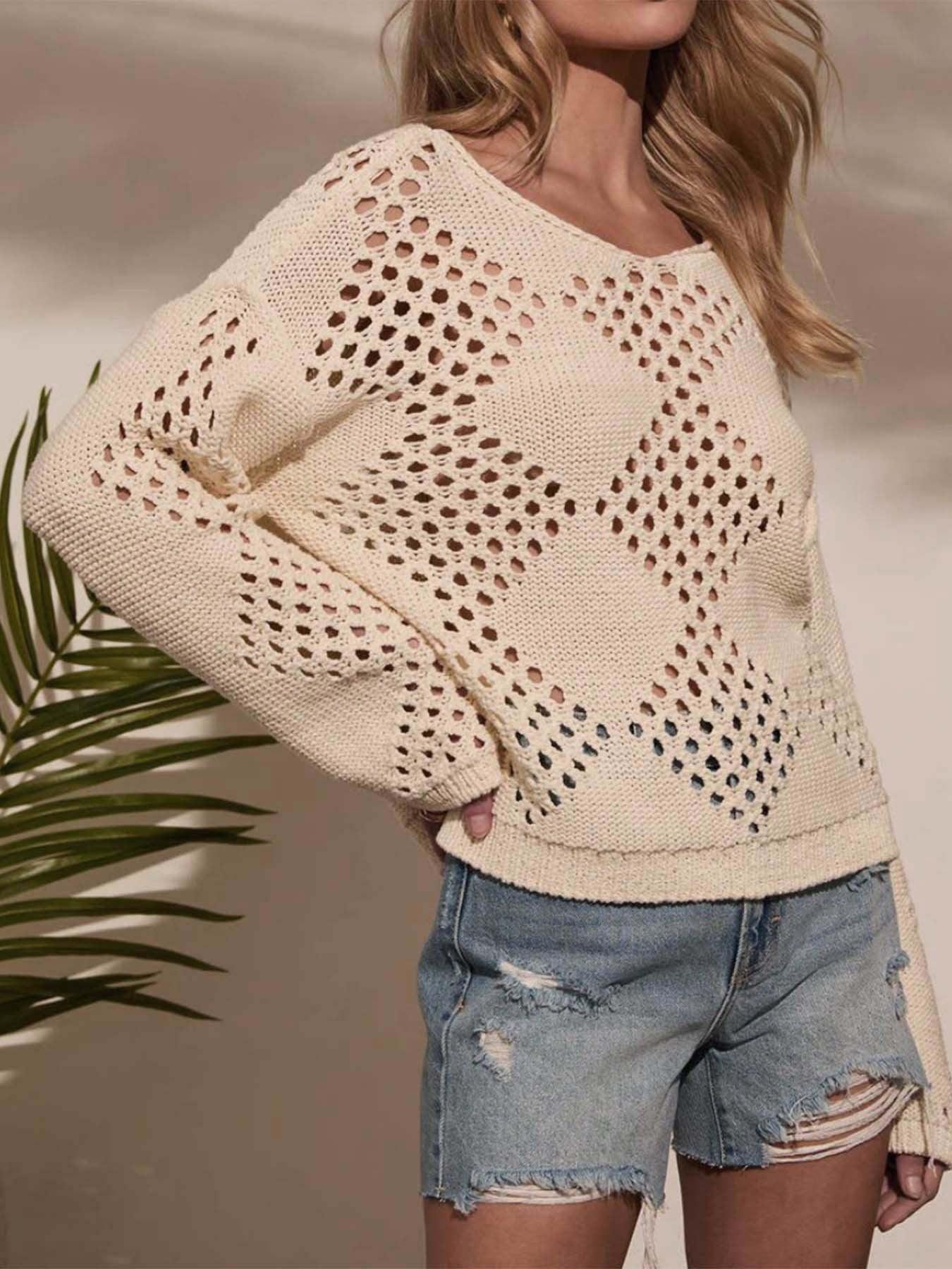 Woman posing in a cream open-knit sweater with diamond stitch detail and denim shorts.