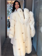 Woman holding a white faux fur coat on a hanger.
