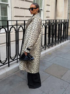 Side view of a woman in a leopard print faux fur coat and black pants.