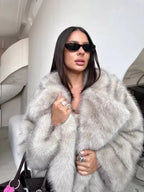 Close-up of a woman wearing a grey faux fur coat, highlighting the plush texture and stylish accessories.