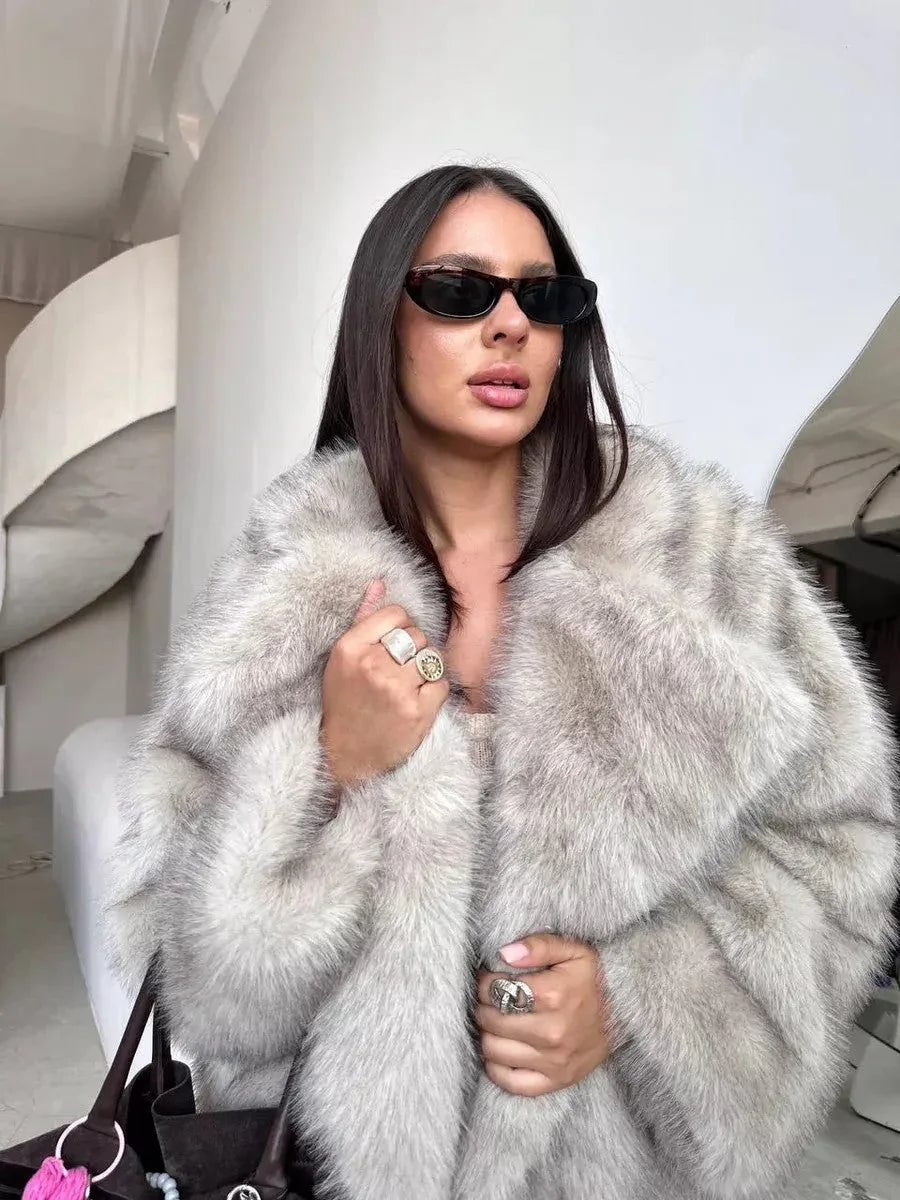 Close-up of a woman wearing a grey faux fur coat, highlighting the plush texture and stylish accessories.