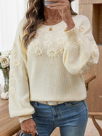 Close-up of a cream knit sweater with intricate 3D floral embroidery.