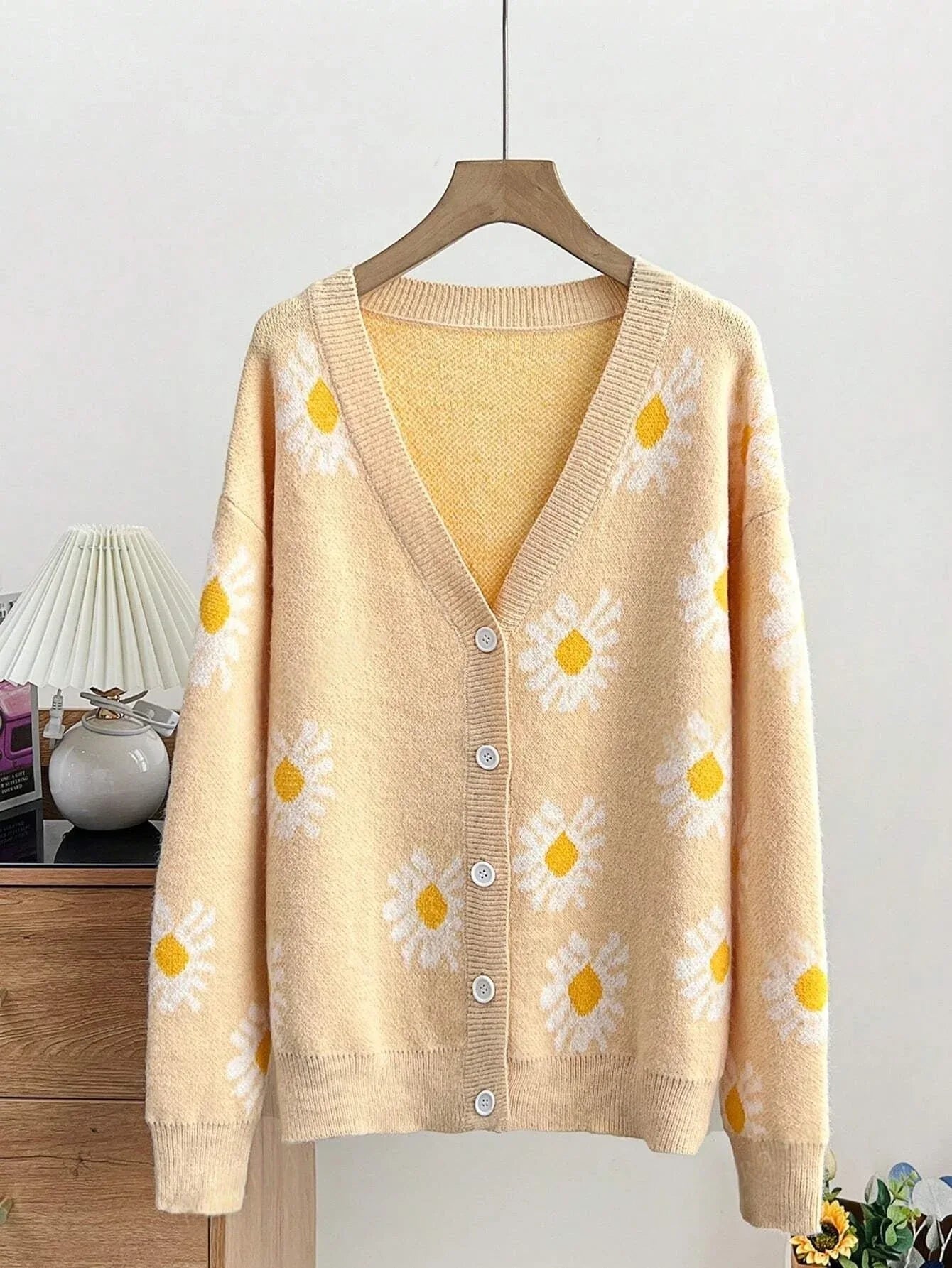 Light yellow long-sleeve cardigan with white daisy print, displayed on a hanger.