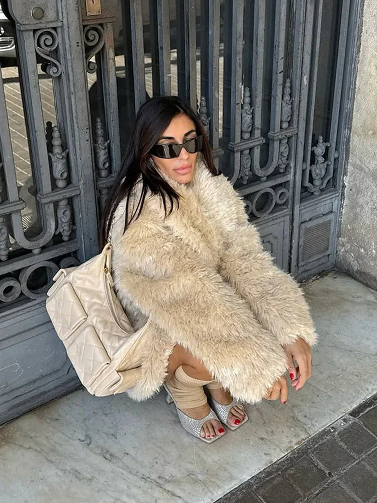 Model posing in a cream fuzzy coat with a cinched waist.