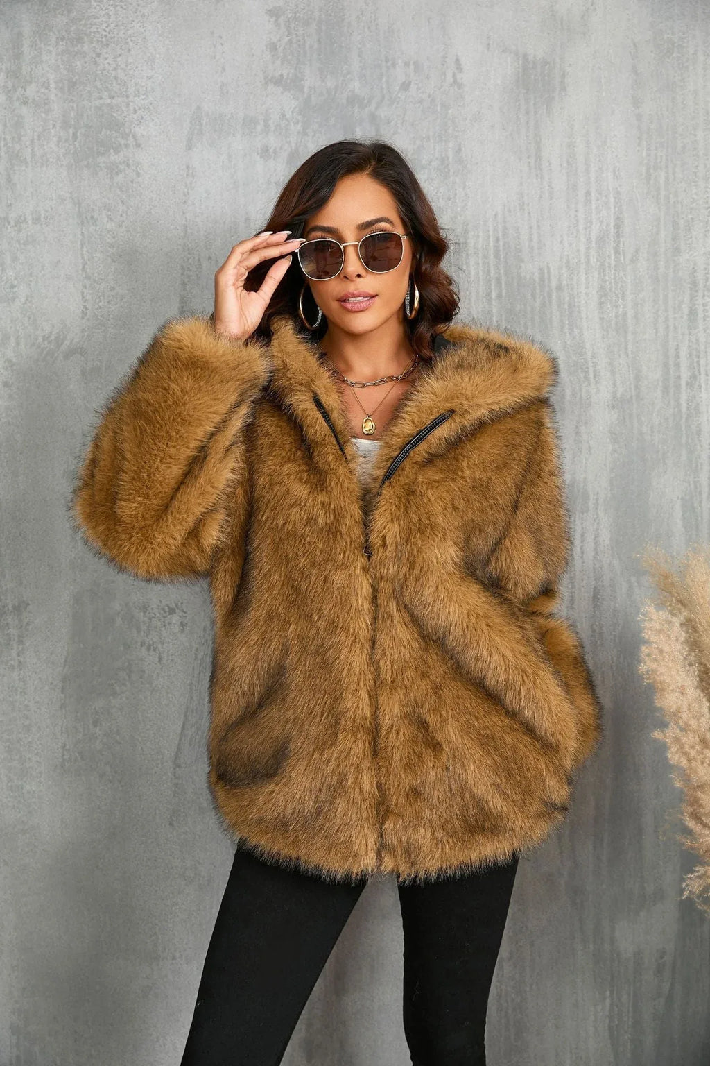 Woman adjusting sunglasses while wearing a brown faux fur hooded jacket