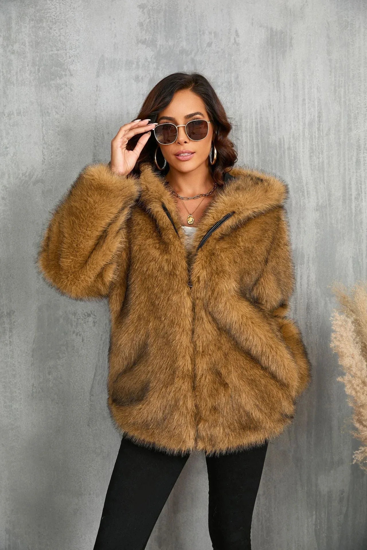 Woman adjusting sunglasses while wearing a brown faux fur hooded jacket