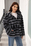 Front view of a woman in a hooded, belted, grey and black striped faux fur jacket.